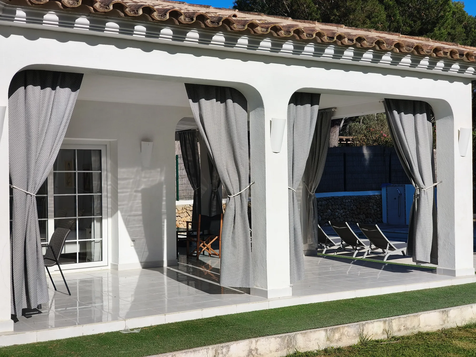 Terrasse aux rideaux et accès à la piscine
